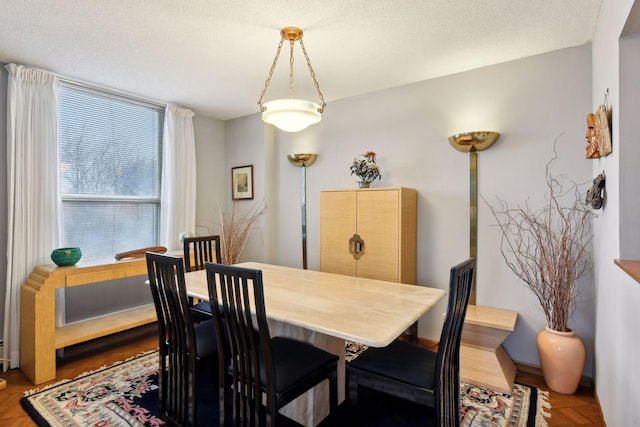 dining room featuring a textured ceiling and parquet flooring