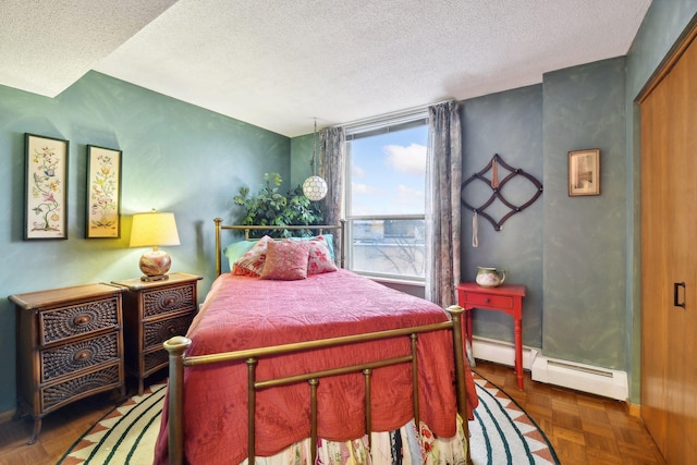 bedroom featuring a closet, dark parquet floors, a textured ceiling, and baseboard heating