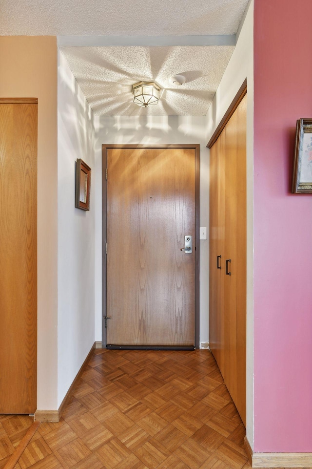 hallway with a textured ceiling and light parquet flooring