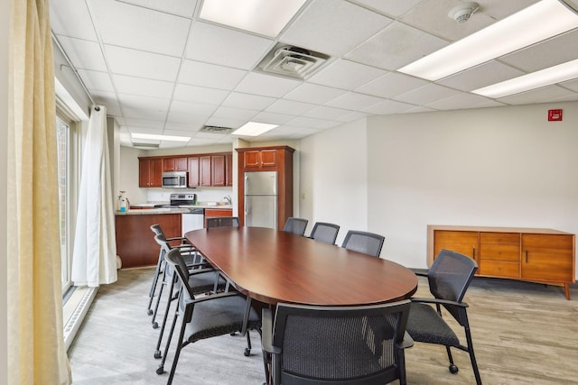 dining space with a drop ceiling and light hardwood / wood-style flooring