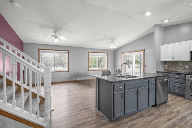 kitchen with backsplash, stainless steel appliances, sink, a center island with sink, and white cabinets