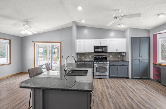 kitchen featuring gas stove, white cabinetry, sink, tasteful backsplash, and lofted ceiling