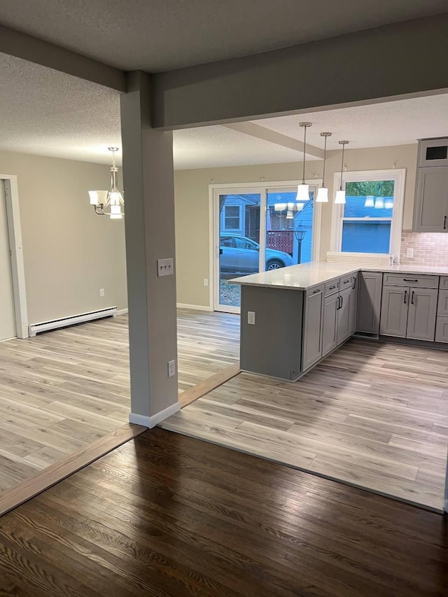 kitchen with tasteful backsplash, a baseboard radiator, gray cabinets, light countertops, and light wood-type flooring