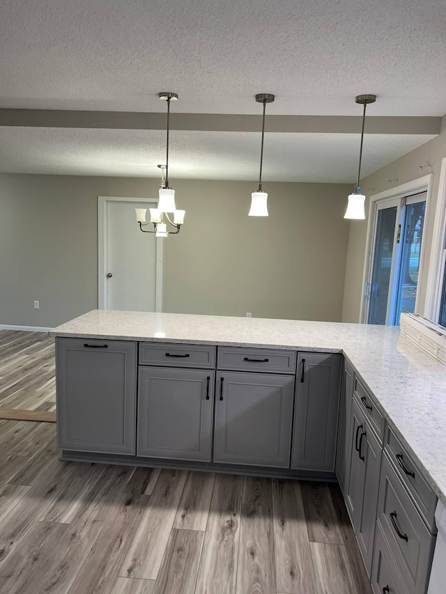 kitchen featuring a textured ceiling, pendant lighting, gray cabinets, and wood finished floors