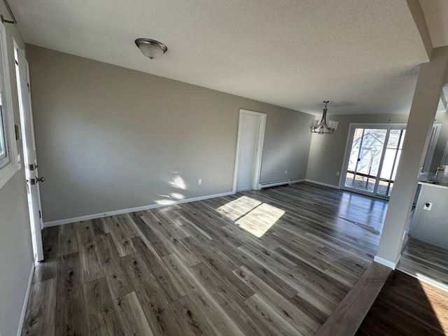 unfurnished dining area with a baseboard heating unit, a textured ceiling, wood finished floors, and baseboards