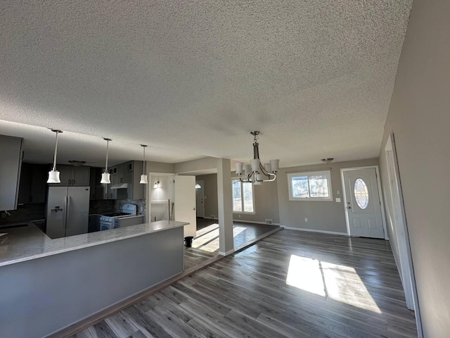 kitchen with dark wood finished floors, white gas stove, a sink, a peninsula, and stainless steel fridge with ice dispenser