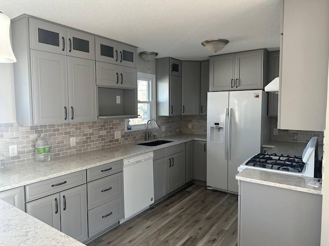 kitchen featuring gray cabinets, glass insert cabinets, a sink, wood finished floors, and white appliances