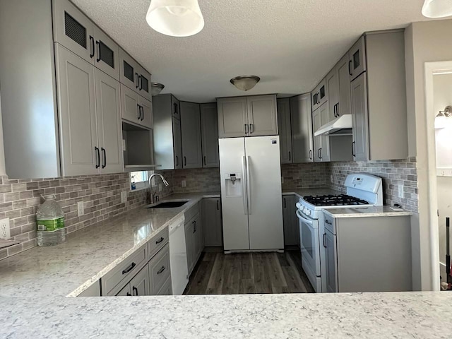 kitchen featuring white appliances, a sink, under cabinet range hood, and decorative backsplash