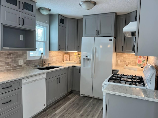 kitchen with white appliances, a sink, under cabinet range hood, and gray cabinetry