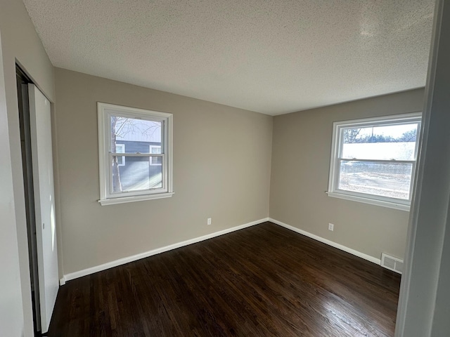 spare room with baseboards, dark wood finished floors, and a wealth of natural light