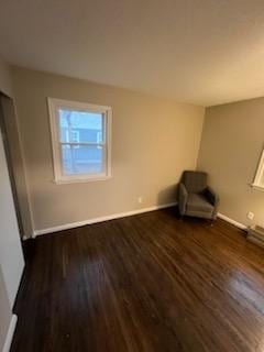 unfurnished room featuring baseboards and dark wood-style flooring