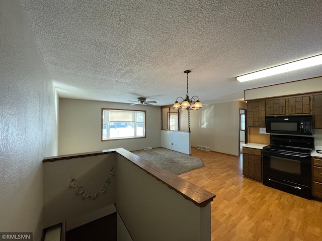 kitchen featuring light hardwood / wood-style flooring, dark brown cabinets, black appliances, a textured ceiling, and decorative light fixtures