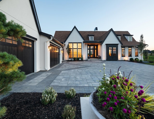 back house at dusk featuring a garage