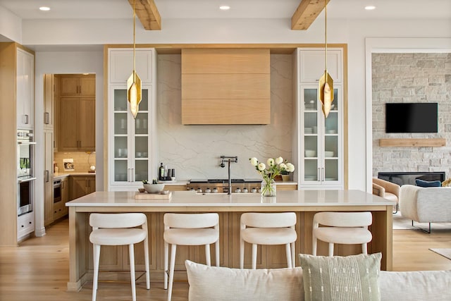 kitchen with beam ceiling, pendant lighting, and light wood-type flooring