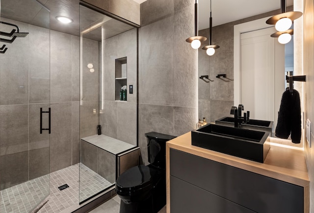 bathroom featuring vanity, toilet, a shower with shower door, and tile walls