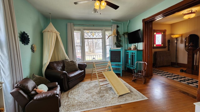 living room with hardwood / wood-style flooring, a ceiling fan, and radiator
