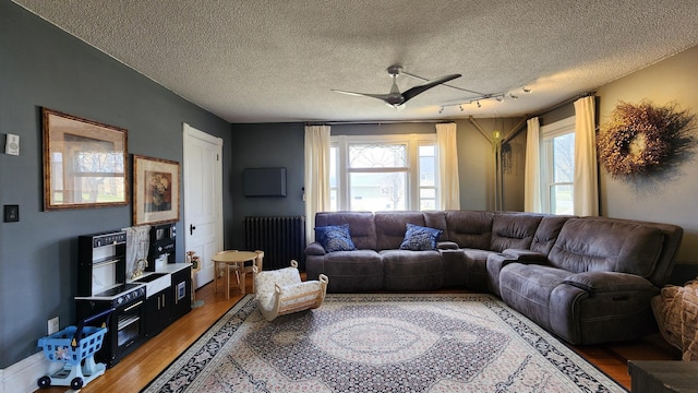 living room featuring a textured ceiling, radiator heating unit, light wood finished floors, and a ceiling fan