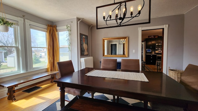dining area with ornamental molding, an inviting chandelier, a textured ceiling, visible vents, and radiator