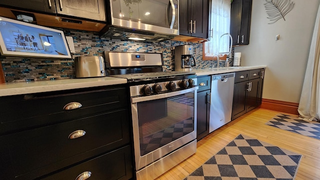 kitchen featuring tasteful backsplash, light wood-type flooring, a sink, and appliances with stainless steel finishes