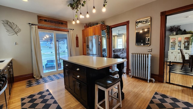 kitchen with stainless steel refrigerator with ice dispenser, light wood-type flooring, and radiator