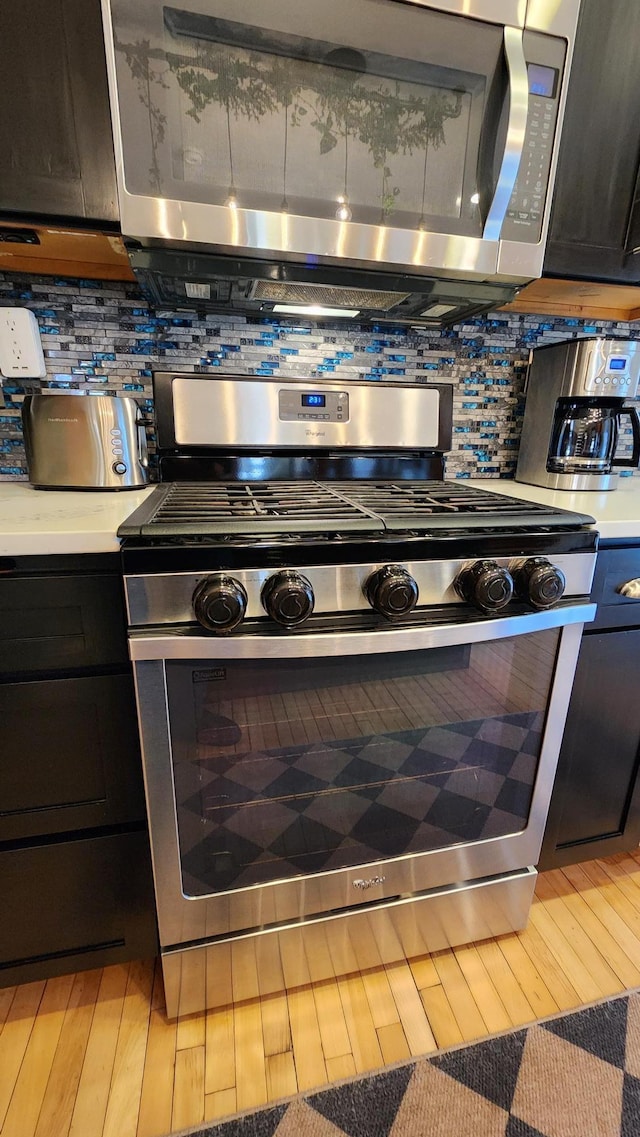 kitchen featuring light countertops, decorative backsplash, light wood-style floors, and stainless steel appliances