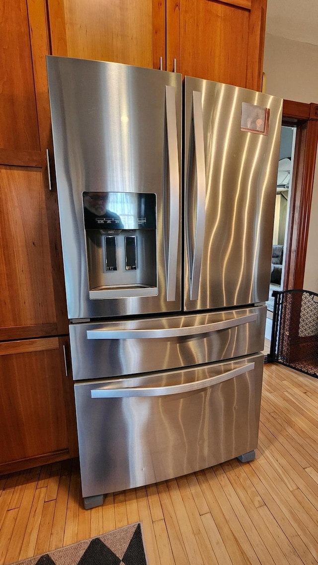 room details with light wood-style floors, brown cabinets, and stainless steel fridge with ice dispenser