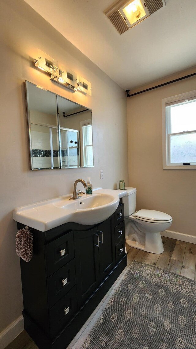 bathroom with vanity, baseboards, toilet, visible vents, and wood finished floors