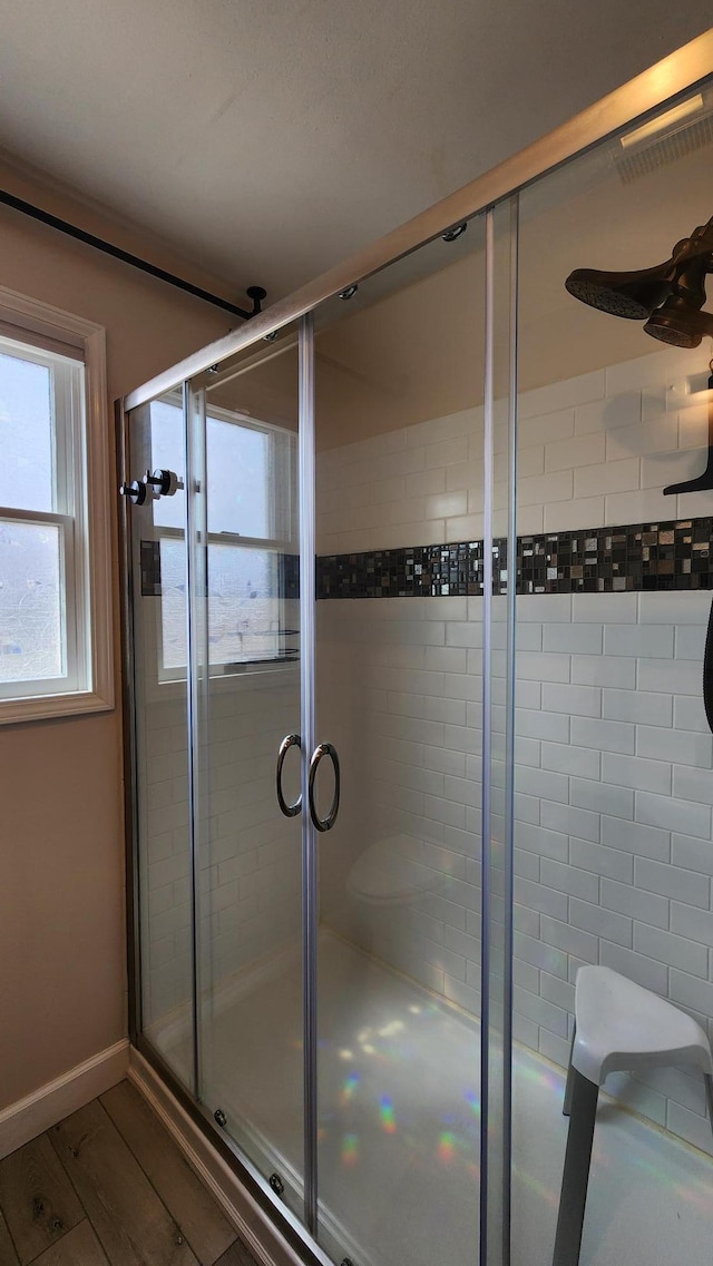 full bath with a shower stall and wood finished floors