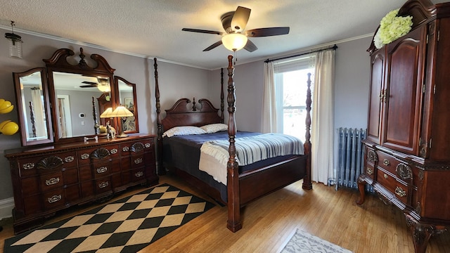 bedroom featuring light wood-type flooring, a textured ceiling, crown molding, radiator, and ceiling fan