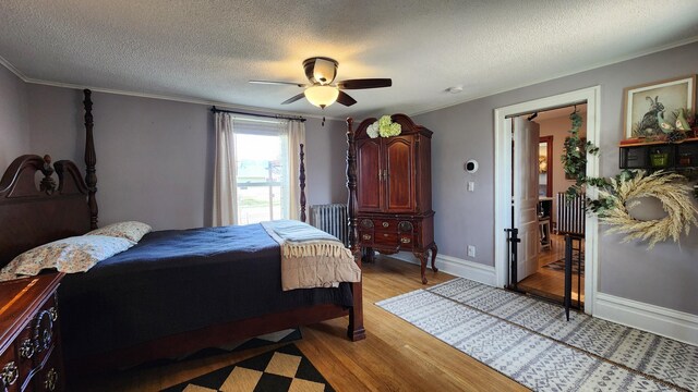 bedroom featuring a textured ceiling, light wood-type flooring, crown molding, and ceiling fan