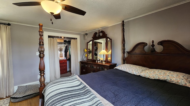 bedroom featuring ceiling fan, a textured ceiling, ornamental molding, and wood finished floors