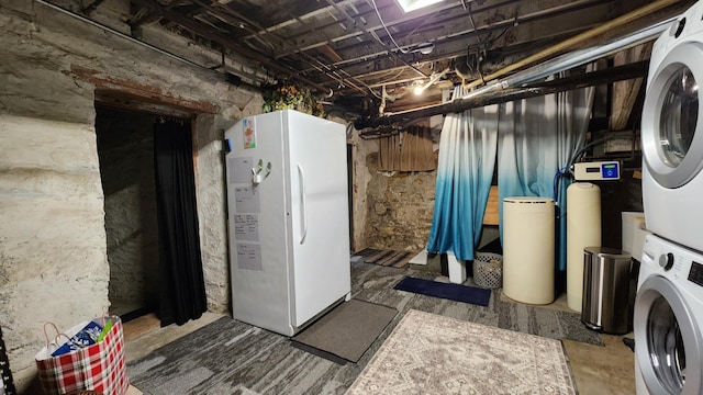 unfinished below grade area with freestanding refrigerator and stacked washer / dryer