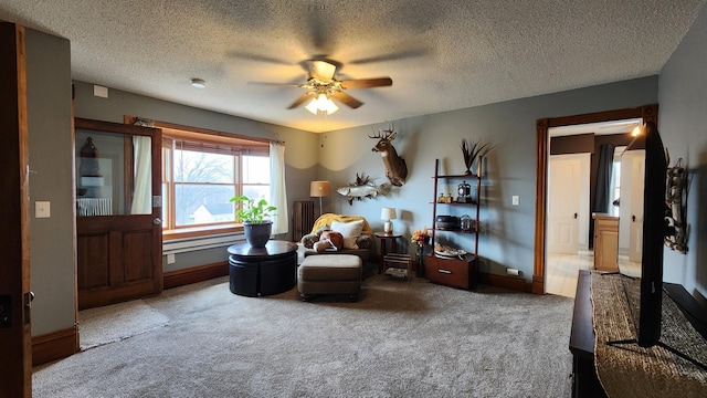 living area with carpet, a textured ceiling, baseboards, and ceiling fan