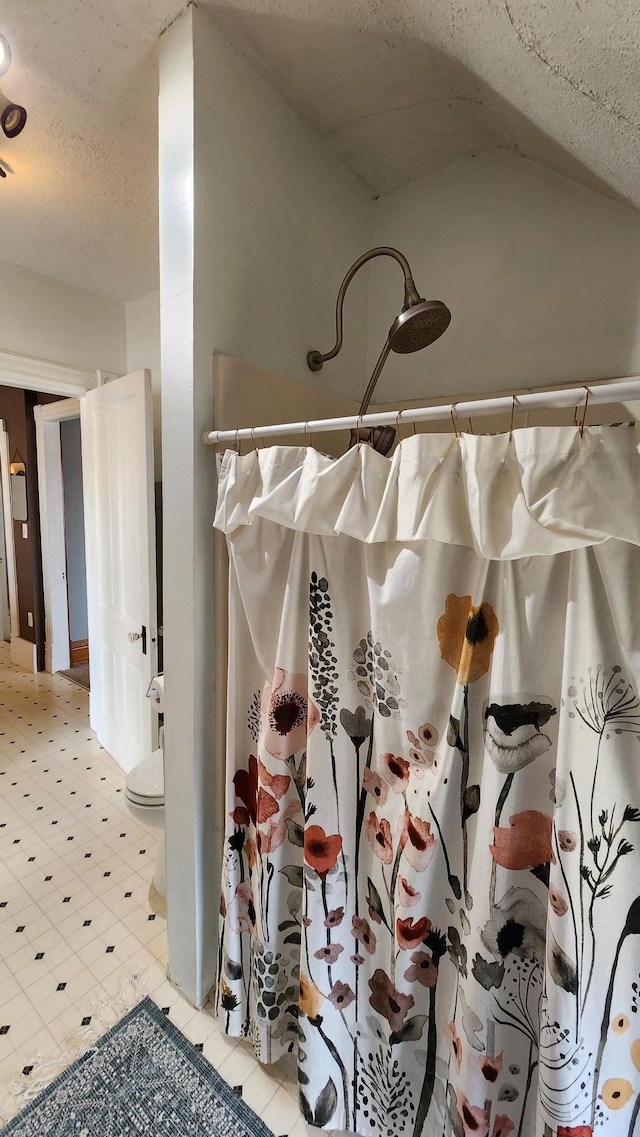 room details featuring toilet, tile patterned floors, a textured ceiling, and curtained shower