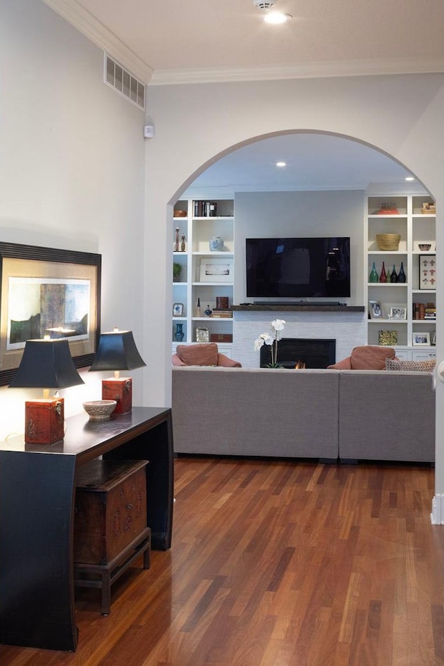 living room with built in shelves, ornamental molding, and hardwood / wood-style floors