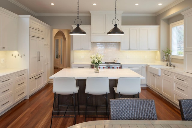 kitchen featuring sink, white cabinetry, stove, a center island, and decorative light fixtures