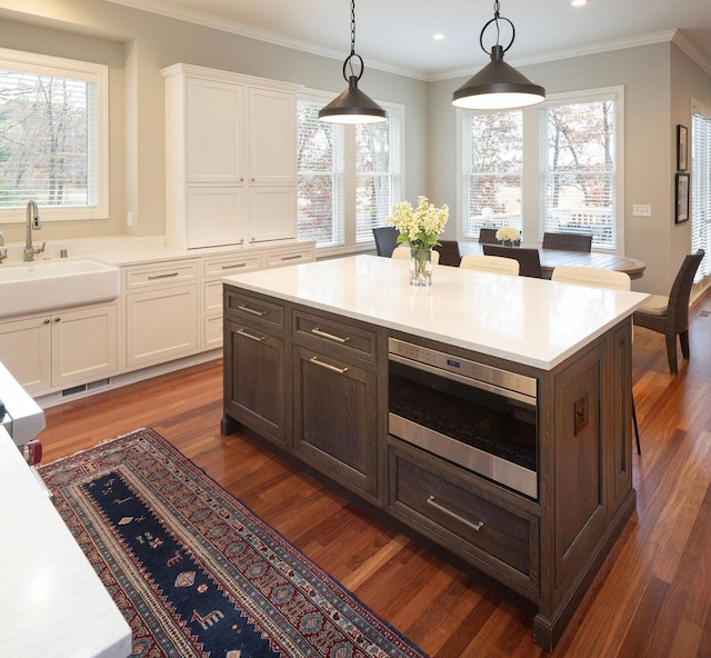 kitchen featuring dark hardwood / wood-style flooring, sink, hanging light fixtures, and white cabinets