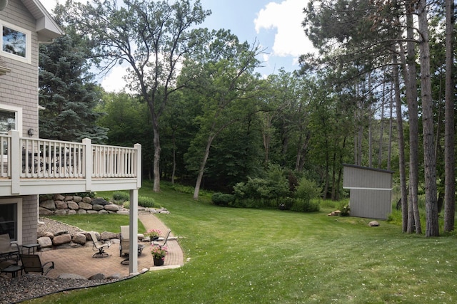 view of yard featuring a patio, a deck, and a storage shed