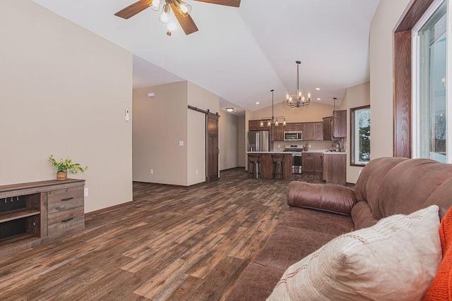 living room with ceiling fan with notable chandelier, dark wood-type flooring, sink, a barn door, and high vaulted ceiling