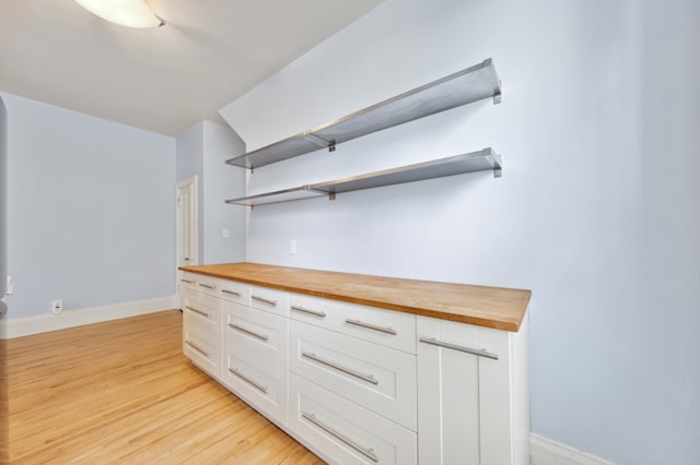 kitchen featuring white cabinets, butcher block countertops, and light hardwood / wood-style floors