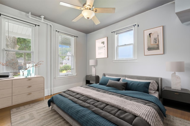 bedroom featuring ceiling fan, multiple windows, and light wood-type flooring