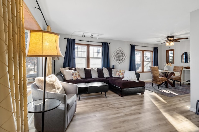 living room featuring baseboards, rail lighting, light wood-style flooring, and a ceiling fan