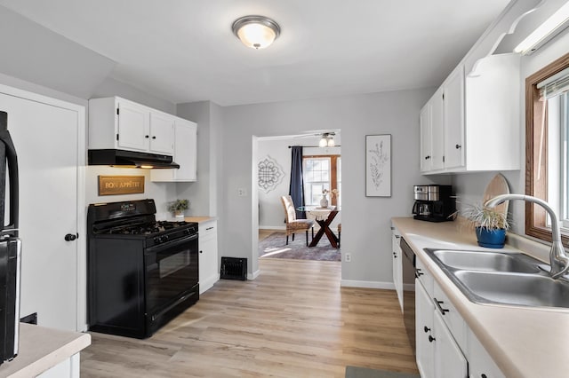 kitchen featuring black range with gas cooktop, under cabinet range hood, a sink, white cabinetry, and light countertops