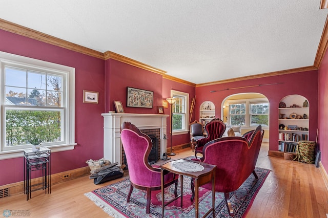 living room featuring crown molding, a fireplace, light hardwood / wood-style floors, and a textured ceiling