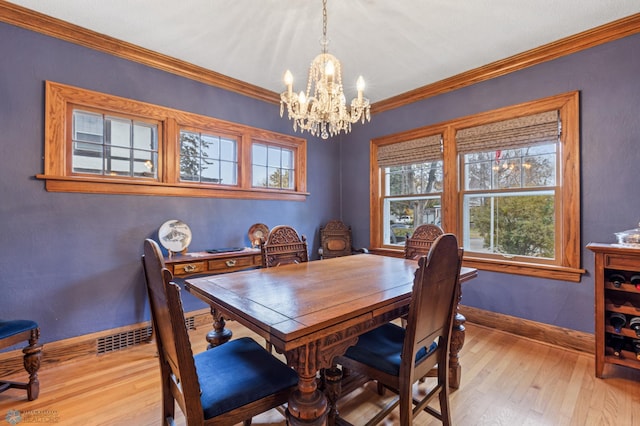 dining space with crown molding, light hardwood / wood-style floors, and a notable chandelier