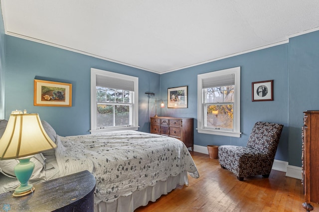 bedroom with wood-type flooring, multiple windows, and crown molding