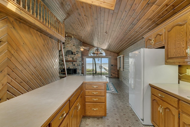 kitchen with freestanding refrigerator, light floors, light countertops, and wood walls