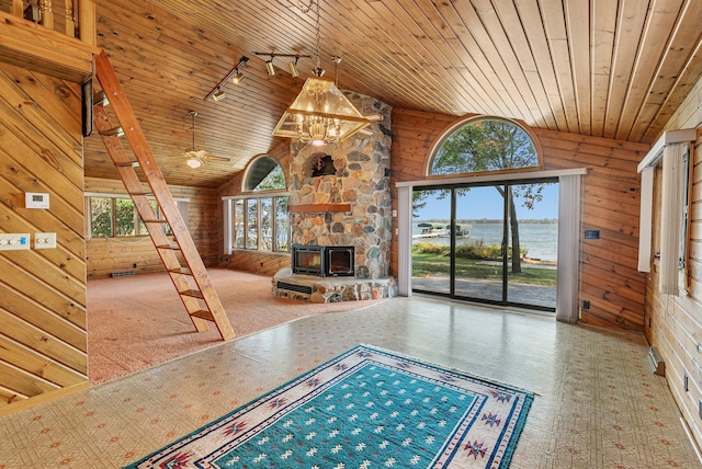 unfurnished living room with high vaulted ceiling, wood ceiling, wood walls, and track lighting