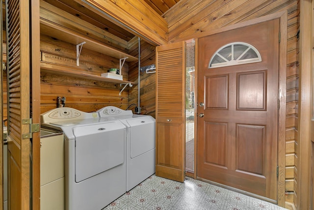 laundry area with laundry area, wooden walls, light floors, and washer and clothes dryer