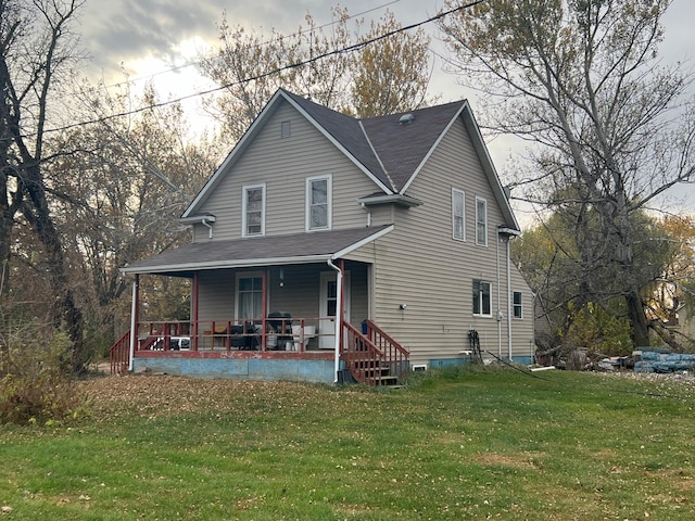 rear view of property featuring a porch and a yard